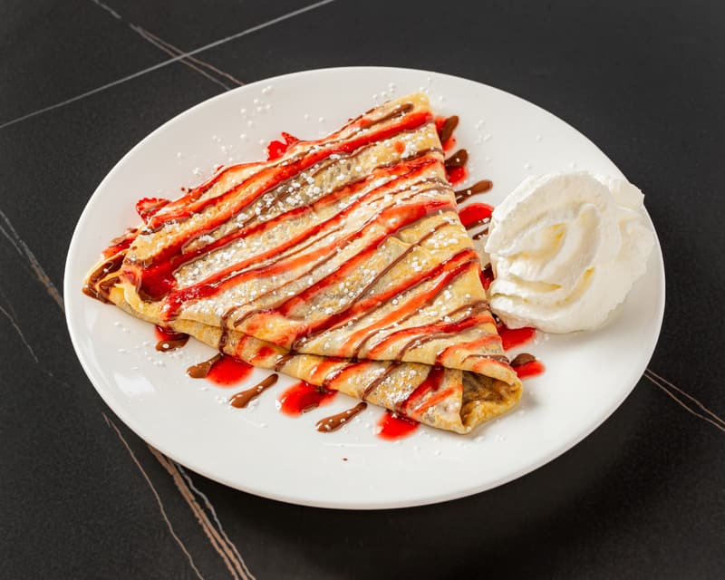 Strawberry Bliss crepe with red strawberry sauce and chocolate drizzle
