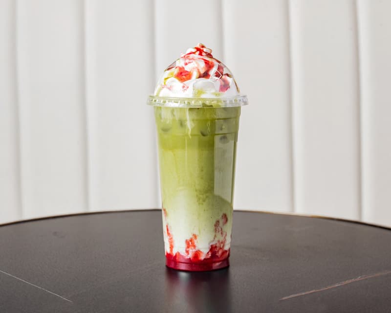 A strawberry matcha, red at the bottom and green on top, with whipped cream